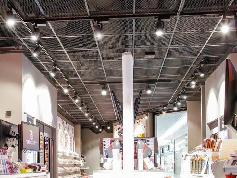 Interieur van een moderne winkel met heldere verlichting, waar verschillende producten op de planken en promotionele displays onder een plafond in industriële stijl worden tentoongesteld.